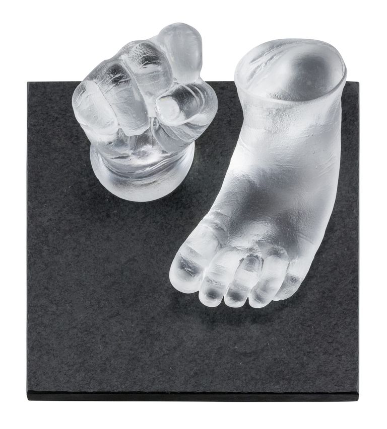 Glass casts of a baby's clenched fist and foot displayed on a thick slate base