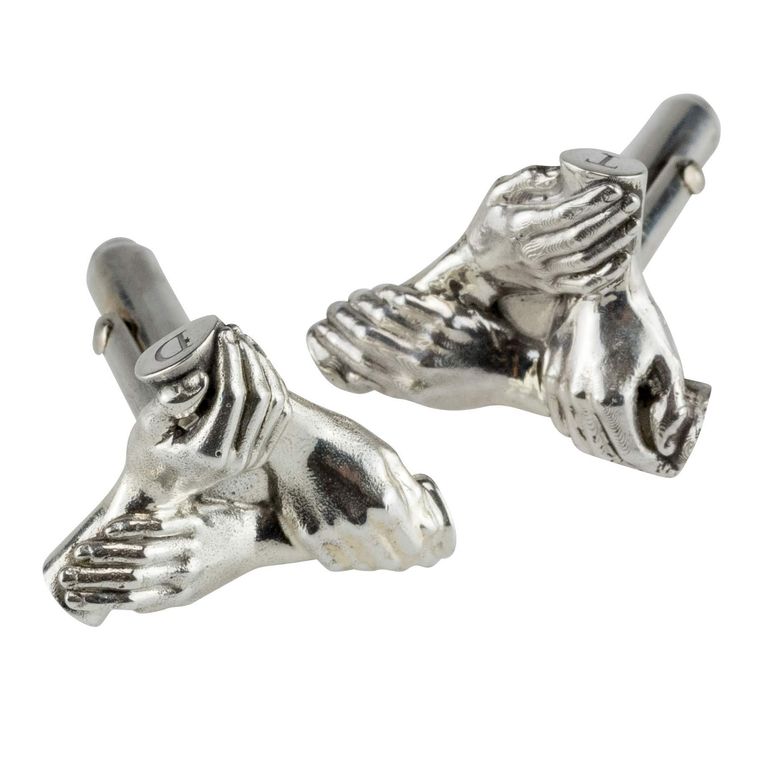 A pair of silver cufflinks of 3 siblings hands linked together