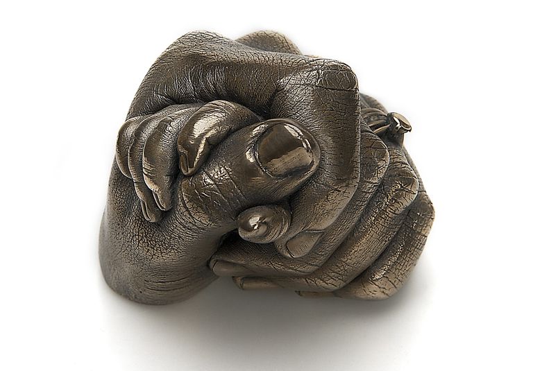 A bronze resin cast of a baby clasping his mum's thumb showing the fine skin detail and mum's rings