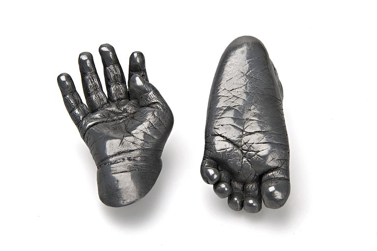 An open hand and upside down foot in aluminium cold cast floating on a white background
