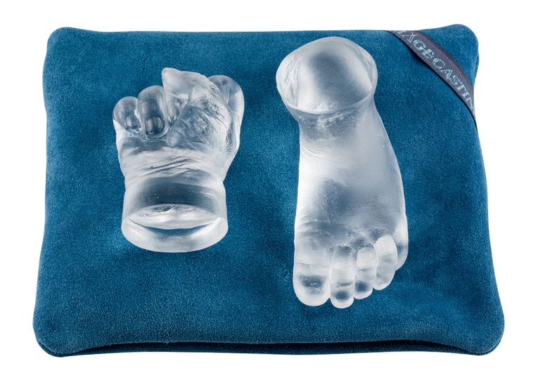 Glass baby hand a foot on a teal cushion