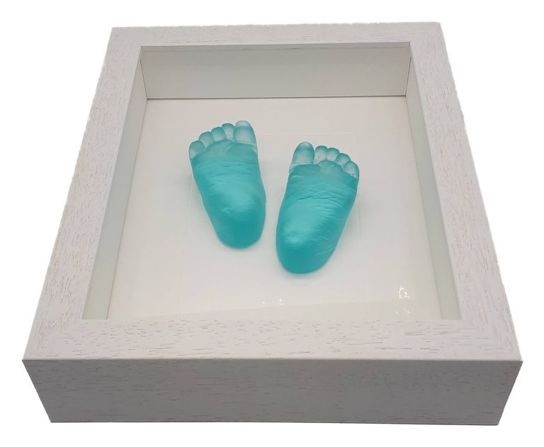 Pale blue glass baby feet in a white box frame angled to catch the light