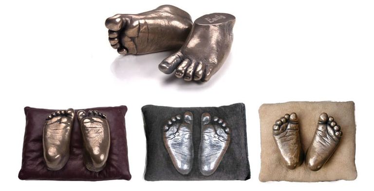 4 sets of pairs of resin baby feet in cold cast bronze and aluminium. 3 pairs displayed on cushion underneath a pair on a simple white background