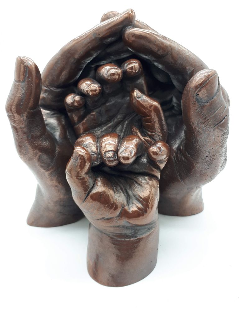 Mum and Dad hands cast in copper resin cusped to protect their two children's hand casts set in front of them